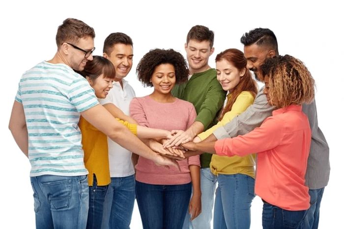 Group of eight smiling with hands extended together.