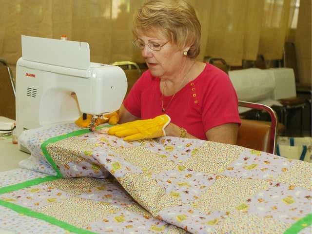 Woman sewing a quilt using a sewing machine.