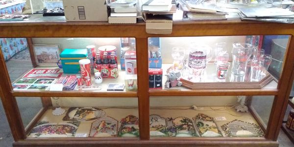 Vintage display case filled with collectible glasses and decorative plates.