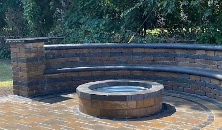 Curved brick outdoor seating area with a central fire pit under trees.