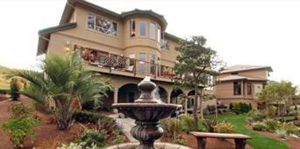 A brown mansion with a water fountain in front of the yard