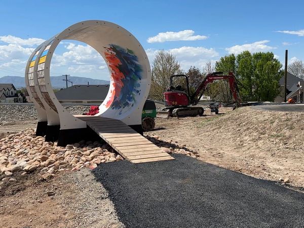 A colorful skateboarding ramp with a curved tunnel and a wooden ramp.