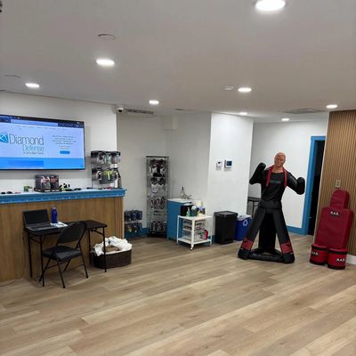 Clean and spacious gym reception area with training equipment and a TV screen.