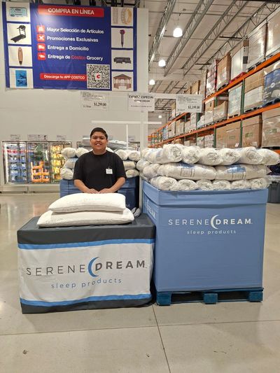 Employee stands behind Serene Dream pillows display in a warehouse store.