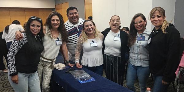 Group of seven people smiling at a conference or meeting.
