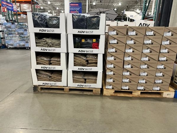 Stacks of ADV Quest apparel boxes and shoeboxes on pallets in a warehouse.