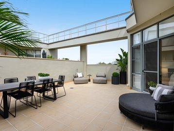 Spacious outdoor patio with modern seating and dining area under clear blue sky.