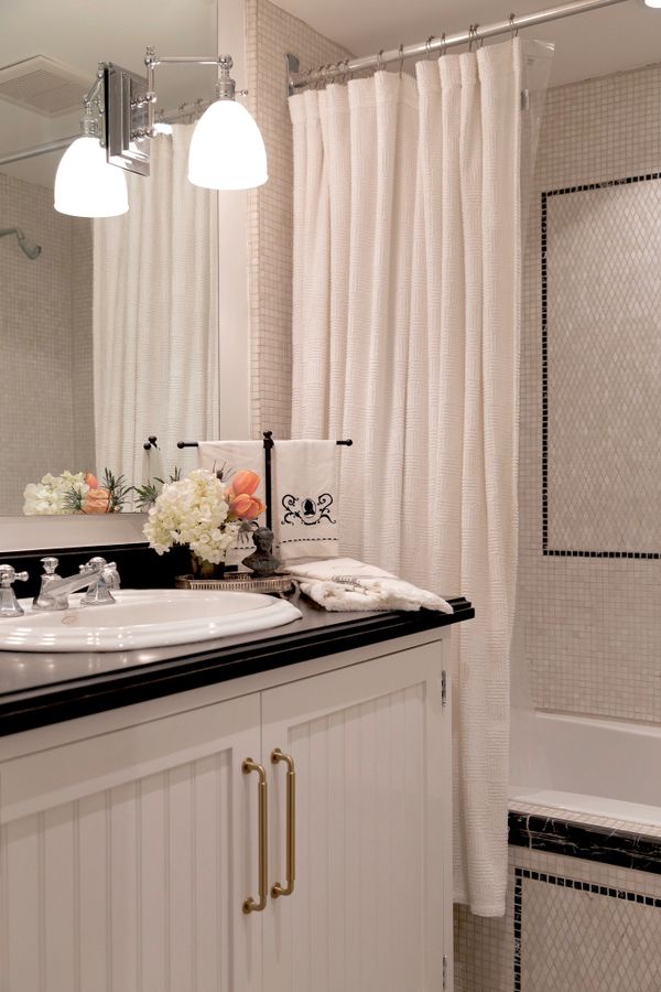 White bathroom with white and black mosaic marble and flowers by the sink 