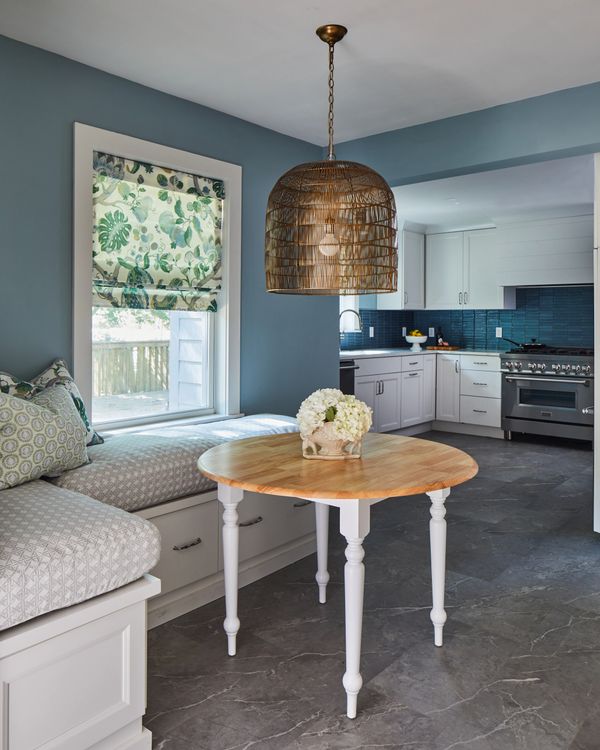 Large print floral fabric over window with large birdcage light fixture over breakfast table