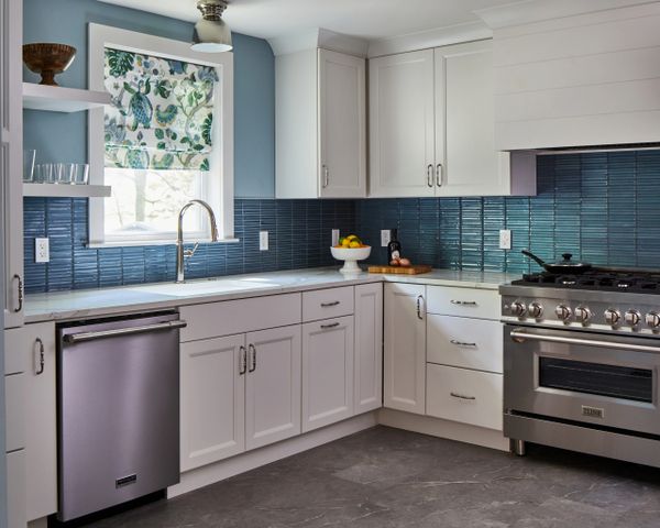 Blue and white kitchen with stainless steel appliances and window over sink 