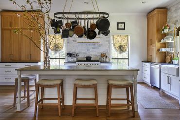 White oak cabinet uppers with white lower cabinets, island, and pot rack 