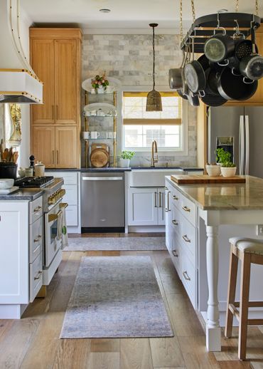 Antique-finished pendant light over sink with pot rack over island 