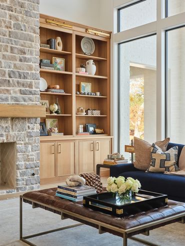 Cozy living room with stone fireplace and wooden shelves.