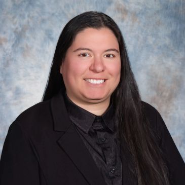Professional portrait of a woman with long dark hair and a black blazer.