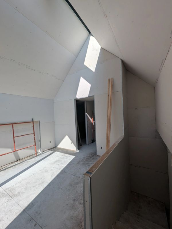 Interior of a bright, unfinished attic with skylight.