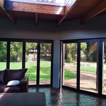 Sunlit living room with large glass doors opening to a green garden.