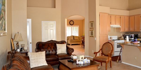 Cozy living room with leather sofas, wooden coffee table, and adjacent kitchen area.