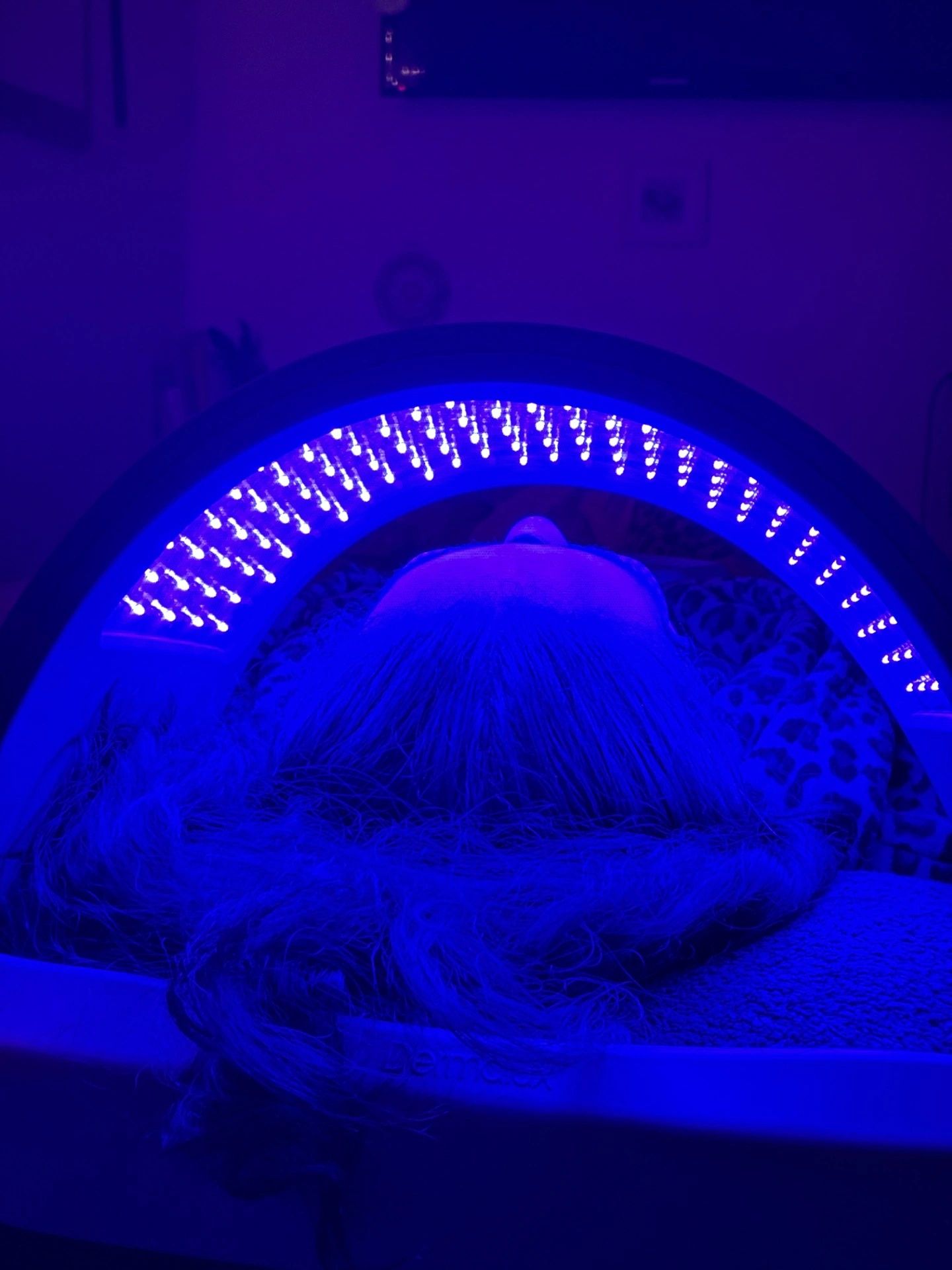 Person undergoing LED light therapy with blue lights focused on the face.