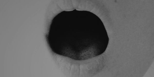 Close-up of an open mouth in black and white.
