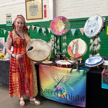 Woman showcasing painted drums at art booth.