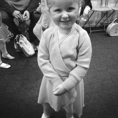 Young dancer wearing ballet wrap cardigan, smiling at camera