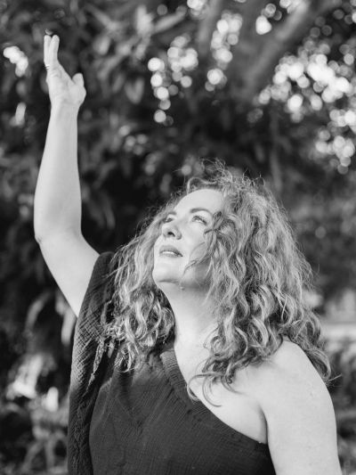 Woman with curly hair raising her arm outdoors.