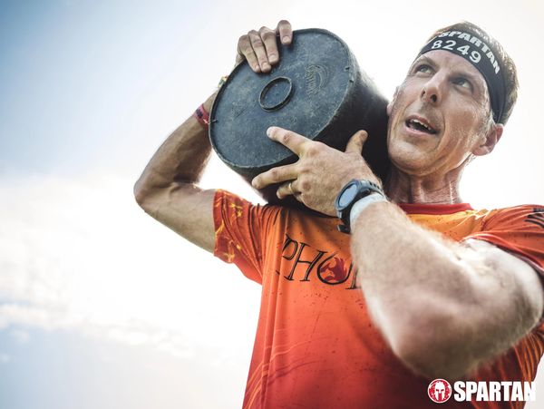 Athlete lifting a heavy weight during a Spartan race event.