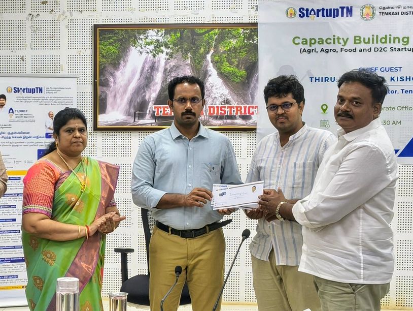 Officials at a Capacity Building Program event in Tenkasi, presenting a certificate or award.