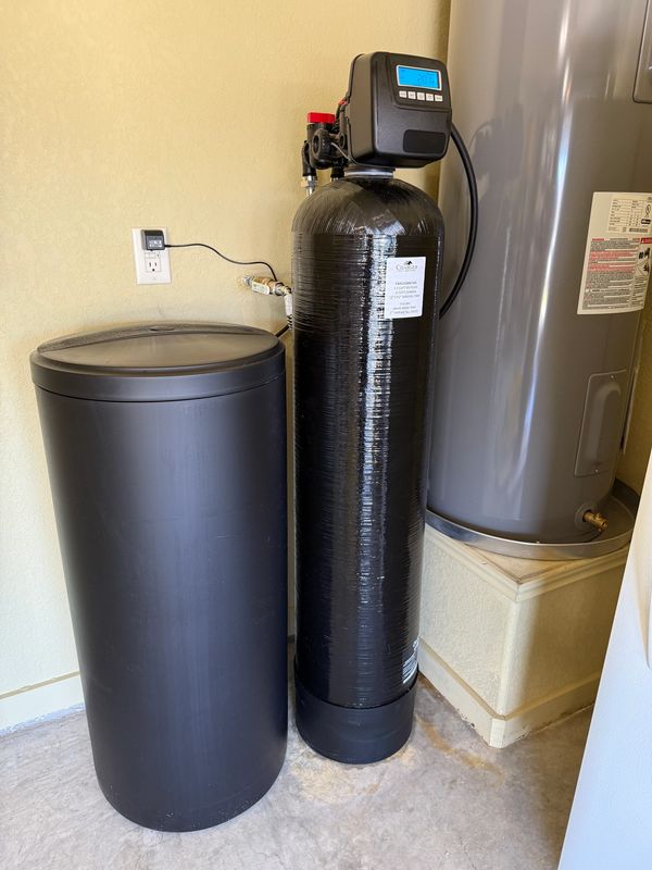 A water softener system installed in a utility room corner.
