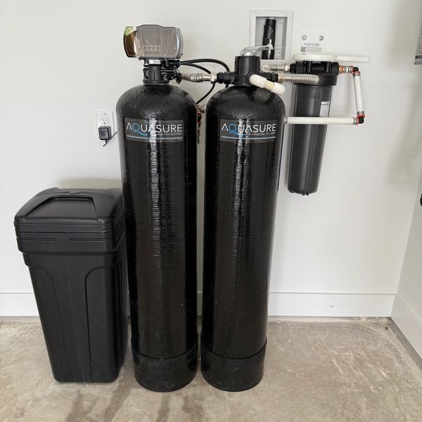 A black Aquasure water filtration system installed indoors.