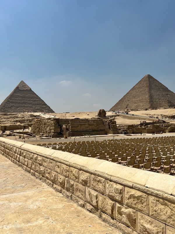 View of the Great Pyramids of Giza with seating setup in front.