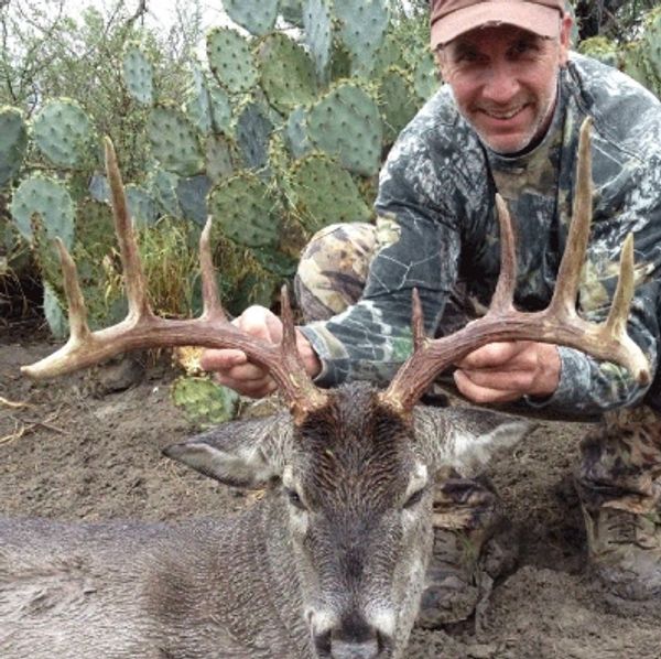 Realtor and hunter Phil Lyons with trophy deer with cactus background