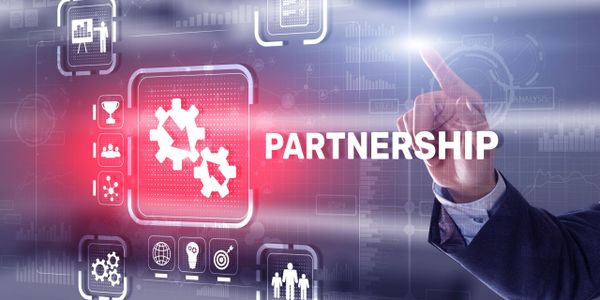 Businessman pointing at the word PARTNERSHIP with technology icons.