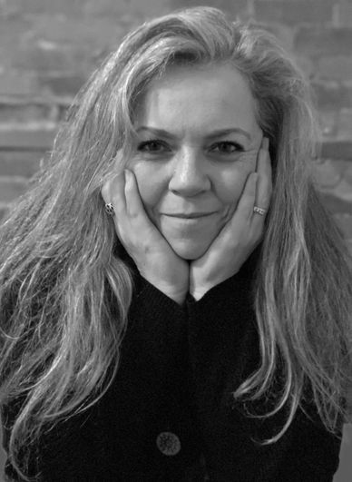 Black and white portrait of a woman with long hair resting her face in her hands.