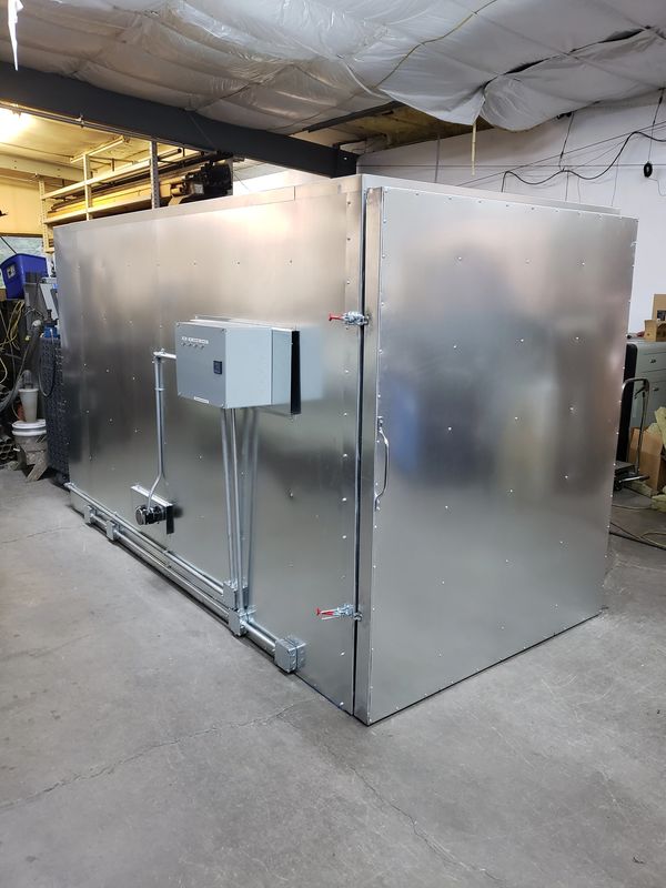 Large metallic industrial enclosure with electrical components in a workshop.