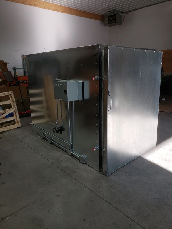 Large metallic industrial box with electrical panel inside a warehouse.