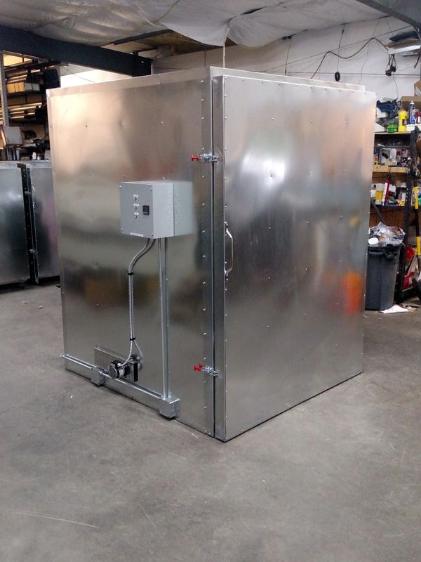 Large metallic industrial chamber with control panel in a workshop.