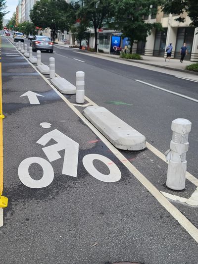 A cycle track on 21st street is protected by concrete.