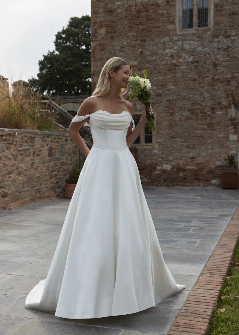 Off-shoulder satin designer wedding dress, wedding dress sale and off-the-rack gowns at K.T. Bridal,