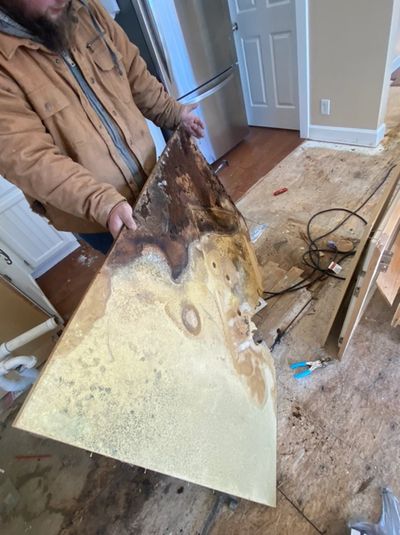 Picture of our employee holding up a piece of dry wall. Showing mold damage. 