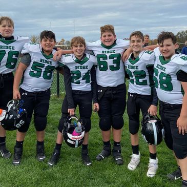 Group of young football players posing outdoors.