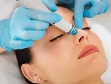 Woman receiving facial treatment with a handheld device.