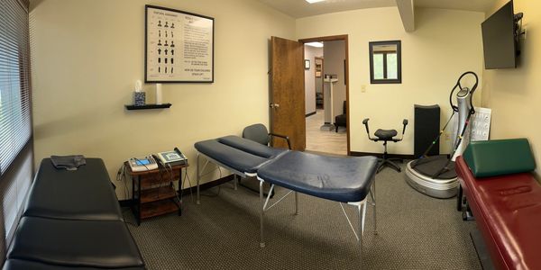 Physical therapy or chiropractic treatment room with therapy tables and equipment.