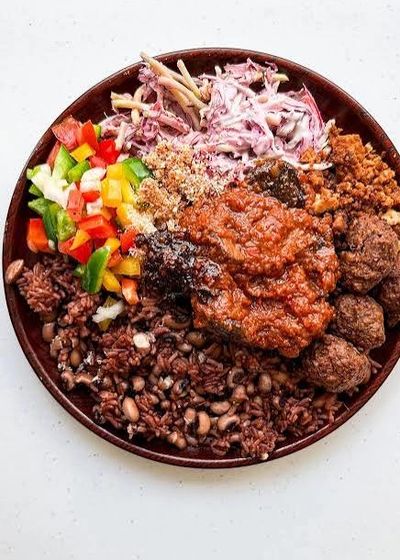 A colorful plate of traditional African food with rice, beans, meat, and vegetables.