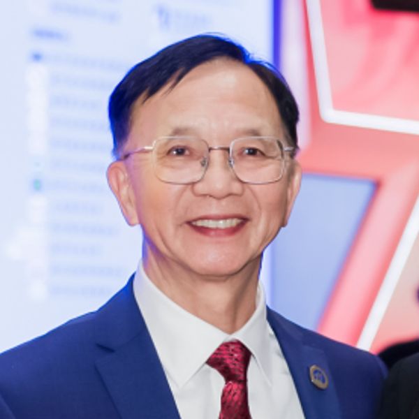 Smiling man in suit and glasses at a formal event.