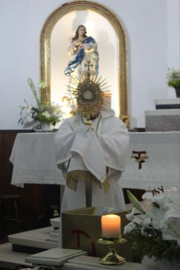 Sacerdote sosteniendo una ostia en una iglesia.