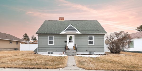 A simple gray house with a green roof during sunset.