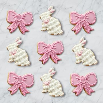 Pink bow and white bunny decorated cookies arranged on a marble surface.