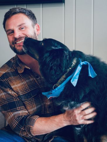 JD Mahan with his dog June at the Destination Finders real estate office in Old Hickory, Tennessee, with June licking his face.