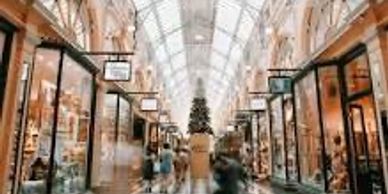 Indoor shopping arcade decorated for Christmas with a large tree at the center.